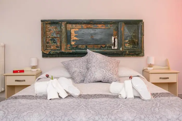 Camera con bagno privato: il letto e i comodini, con la testiera in legno dipinto